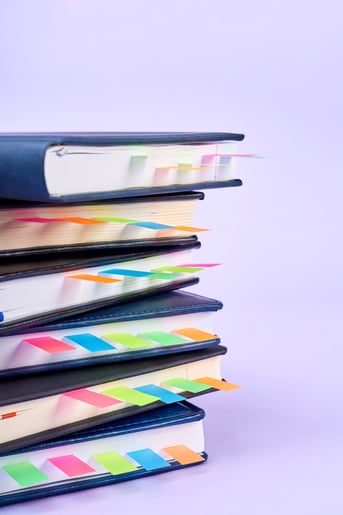closeup-stack-office-notepads-with-colorful-sticky-page-markers-sandwiched-pages