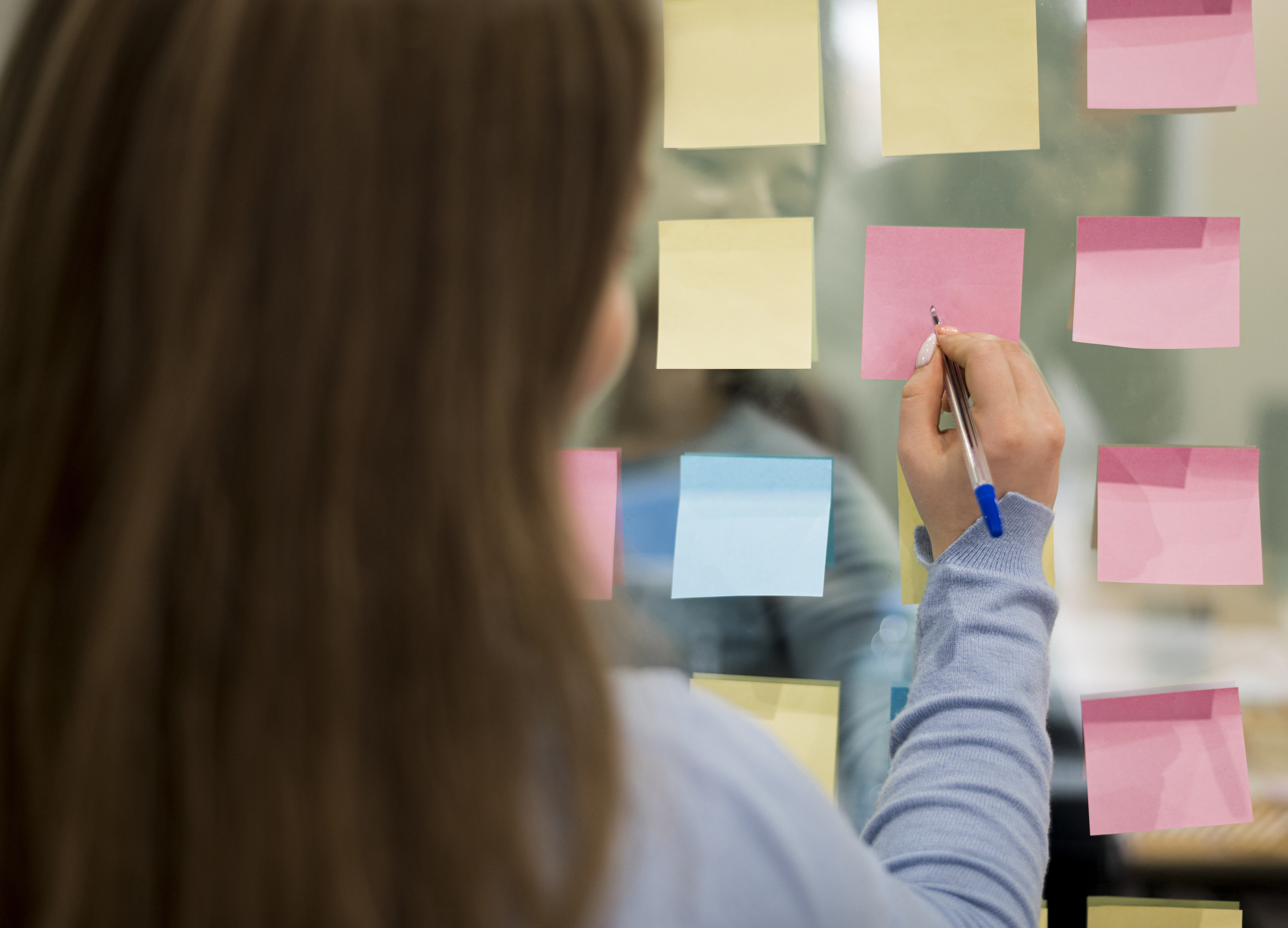 back-view-woman-office-writing-sticky-notes