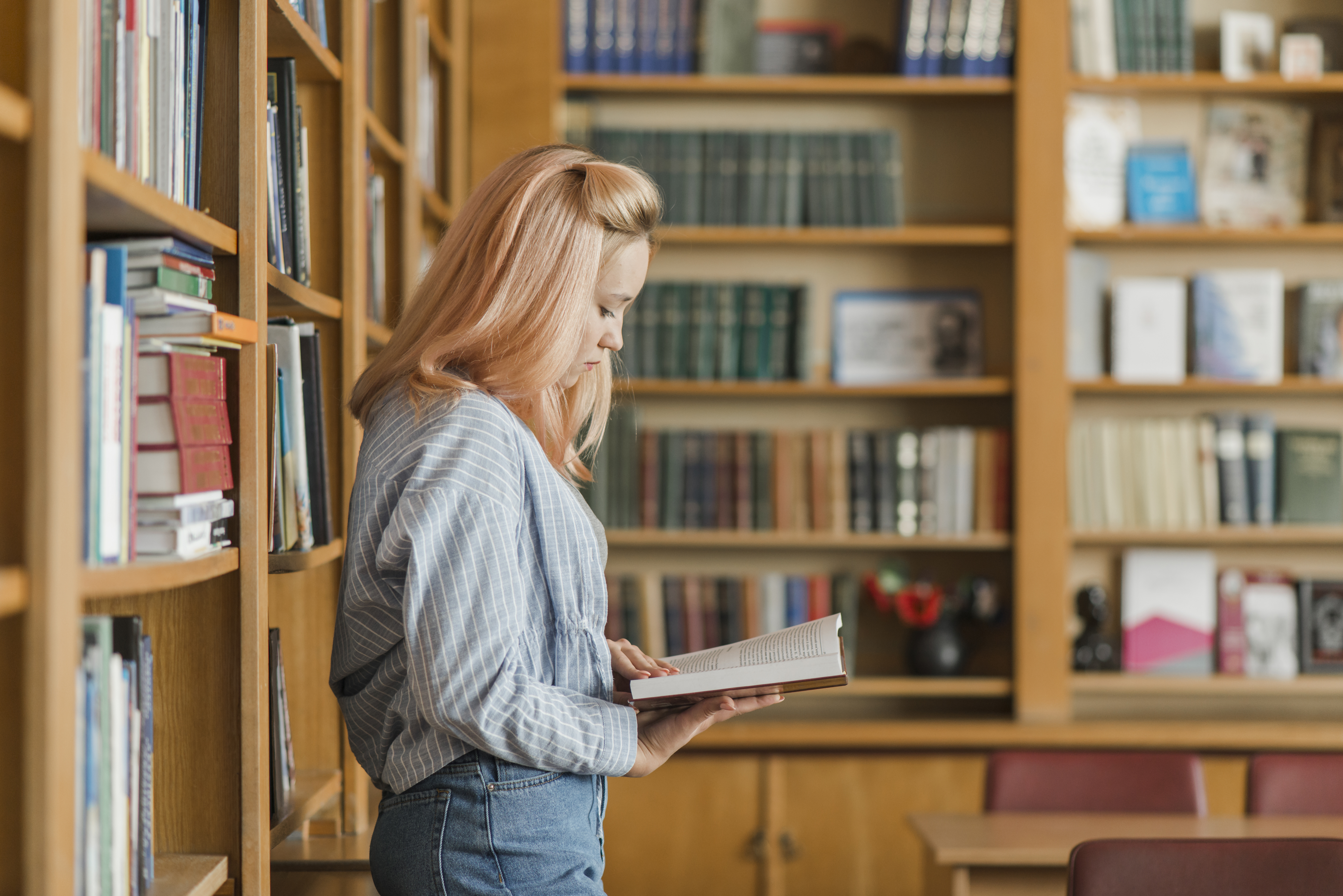 teenager-reading-near-bookshelves
